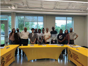 students standing around tables with yellow tablecloths